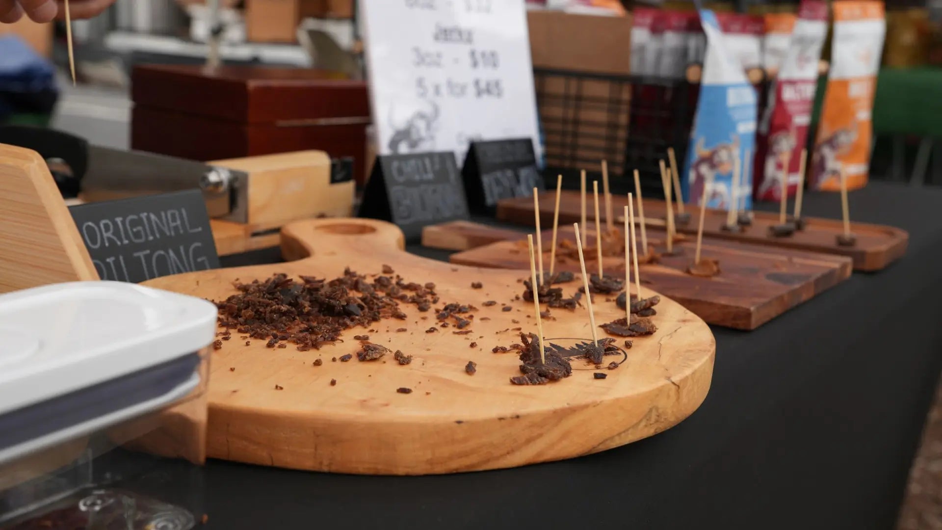 Biltong and beef jerky samples displayed on wooden boards at a farmers market